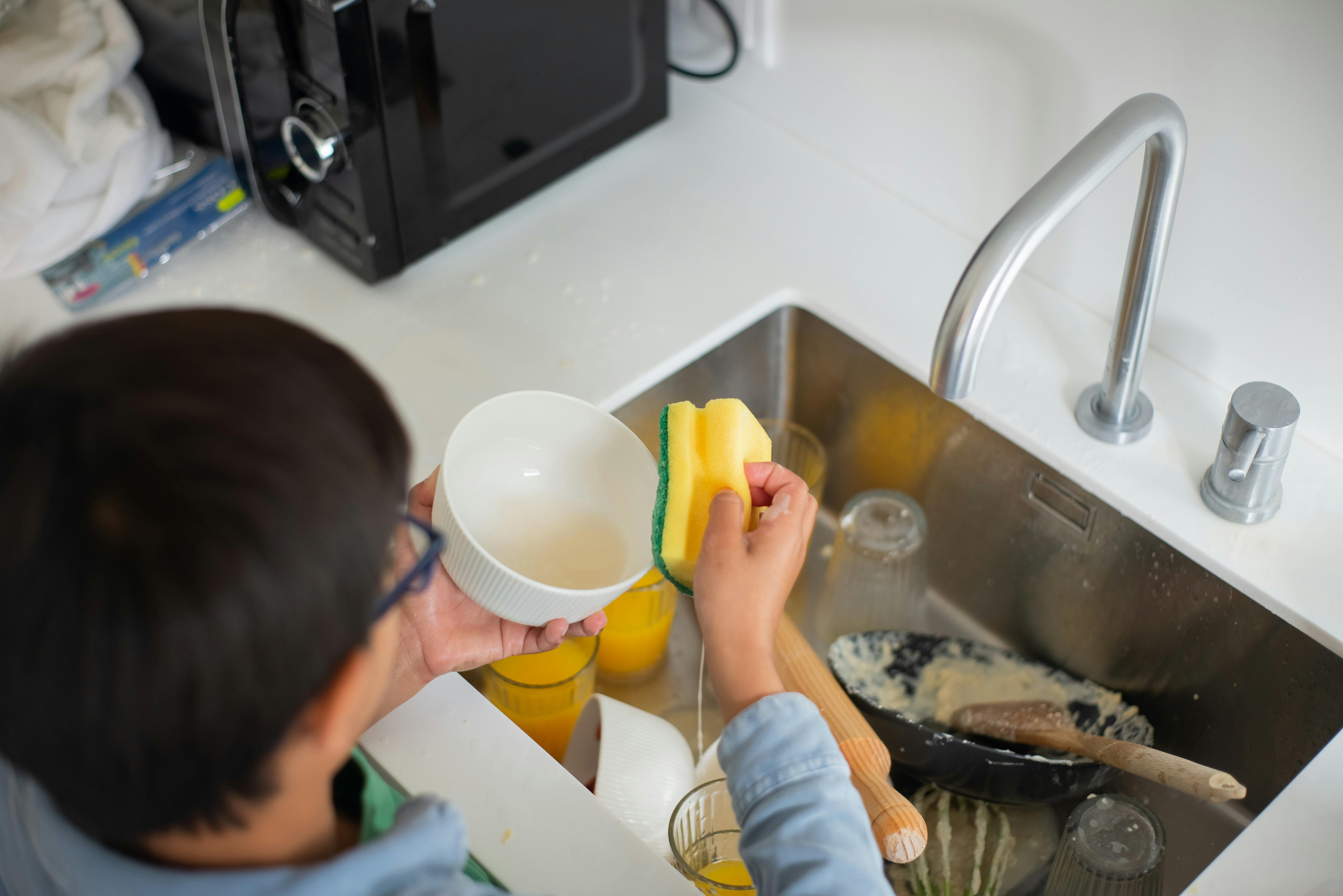 A boy focused on washing dishes.