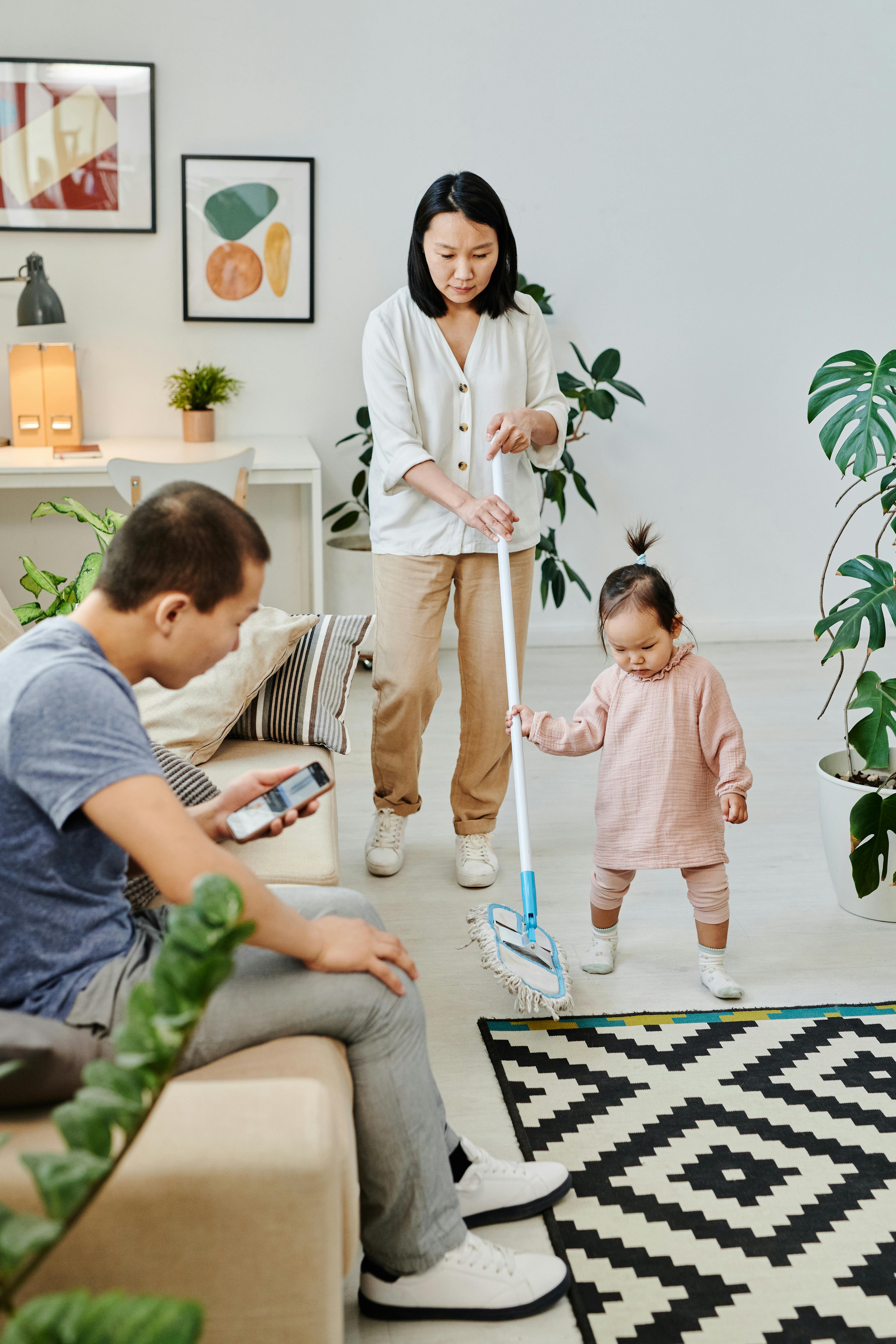 A parent cleaning while another family member relaxes nearby.