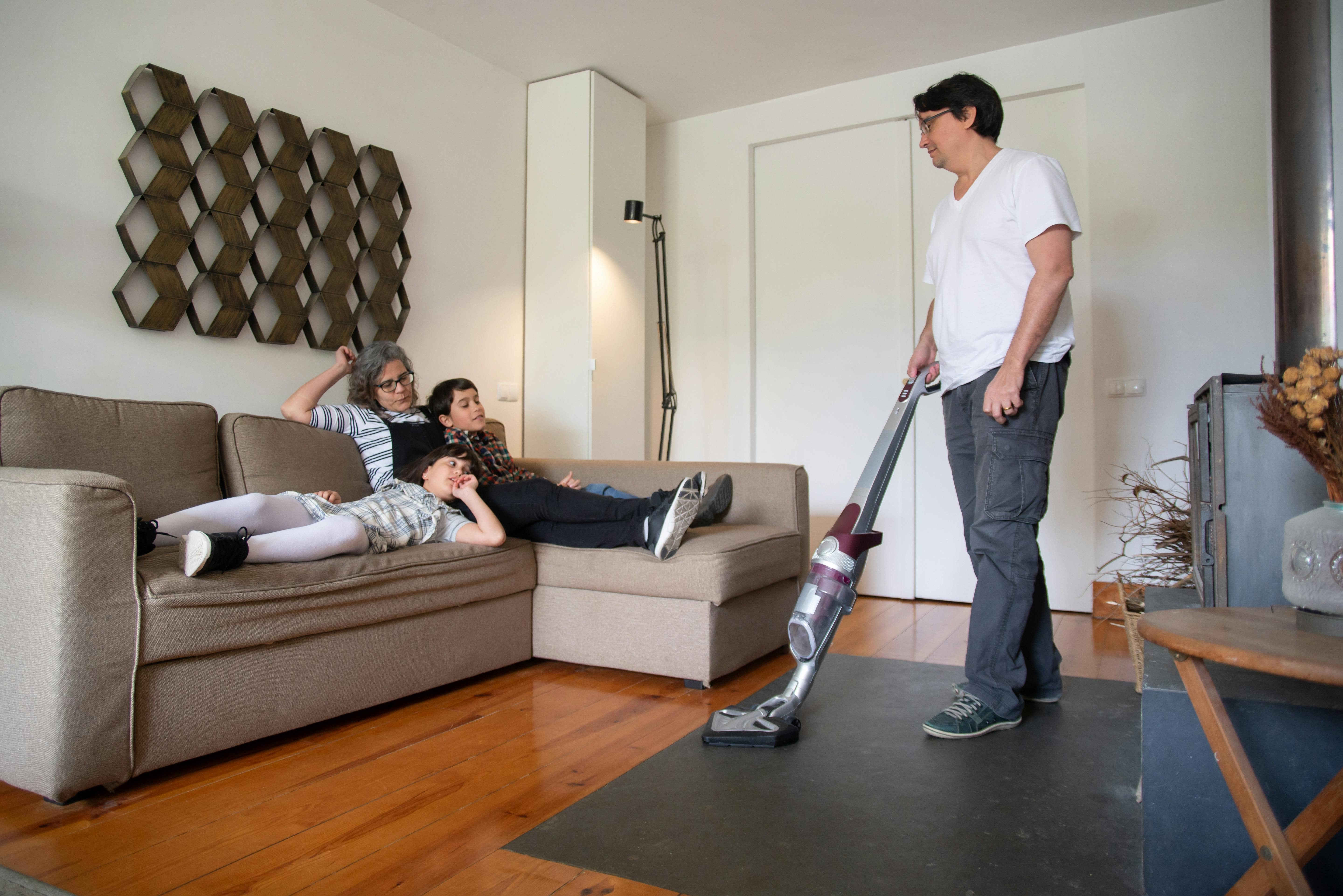 An adult vacuuming in a living room during a daily routine.