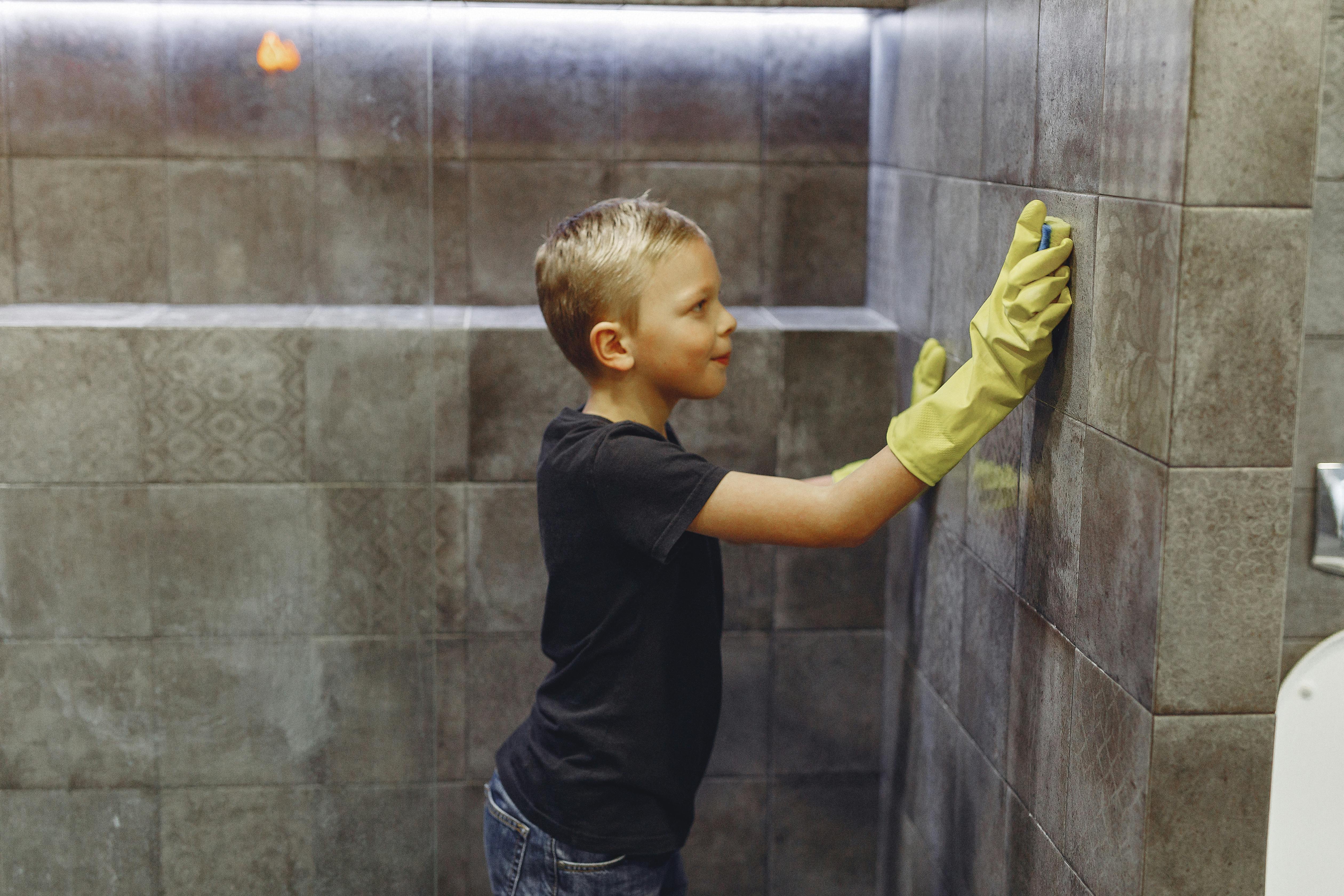 A child independently cleaning bathroom tiles.