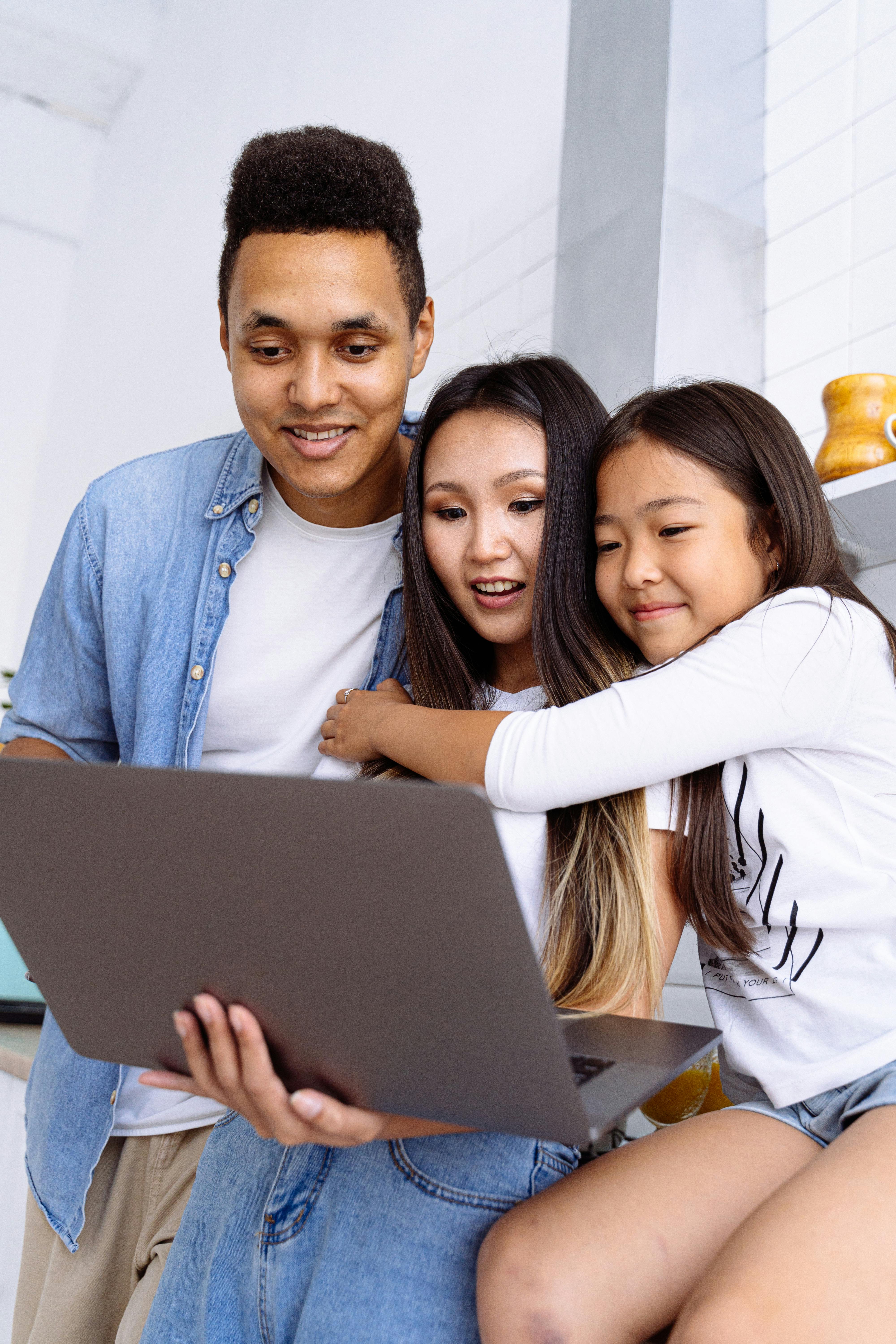 A family gathered around a laptop together in a bright kitchen